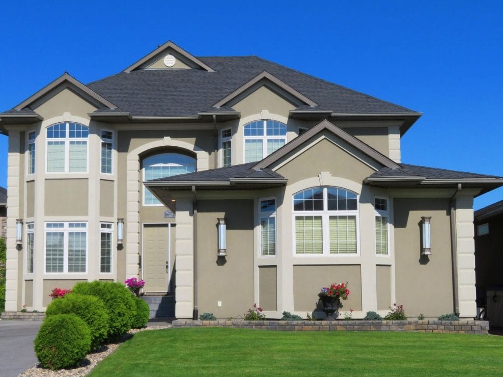 A large house with a spacious yard and driveway, featuring Toronto Doors and Windows branding.